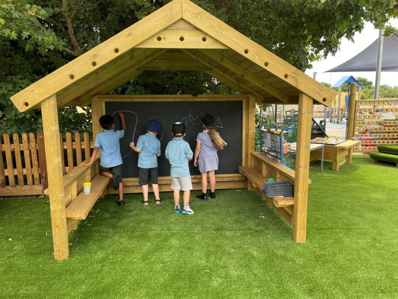 four children in light blue school uniform stand inside the giant playhouse