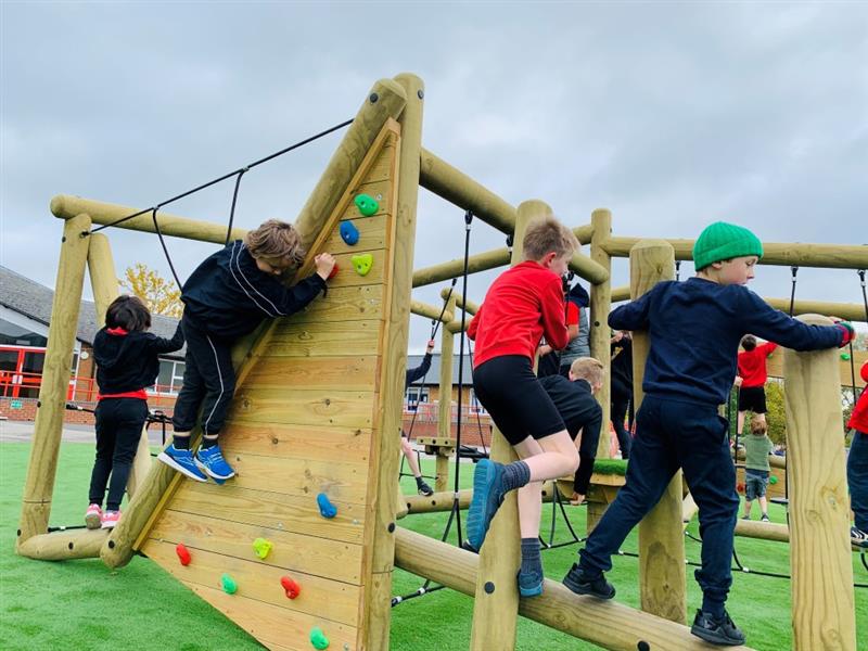 children in red and black school uniform on the climbing wall and the balance beam