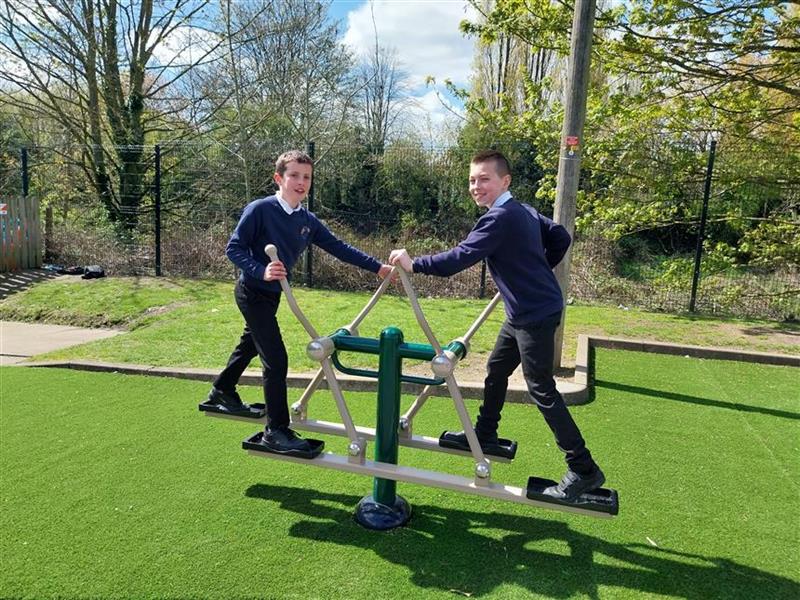 2 children playing on the outdoor gym in their playground