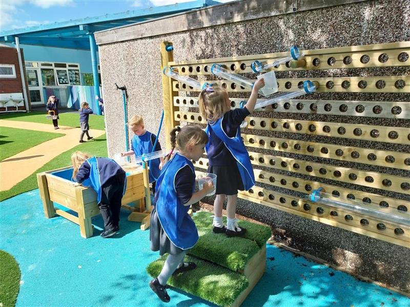 children playing on their water wall in their playground