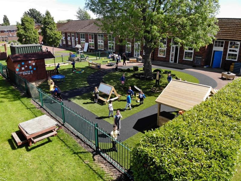 a drone shot of the playground with children playing round on the different bits of the equipment