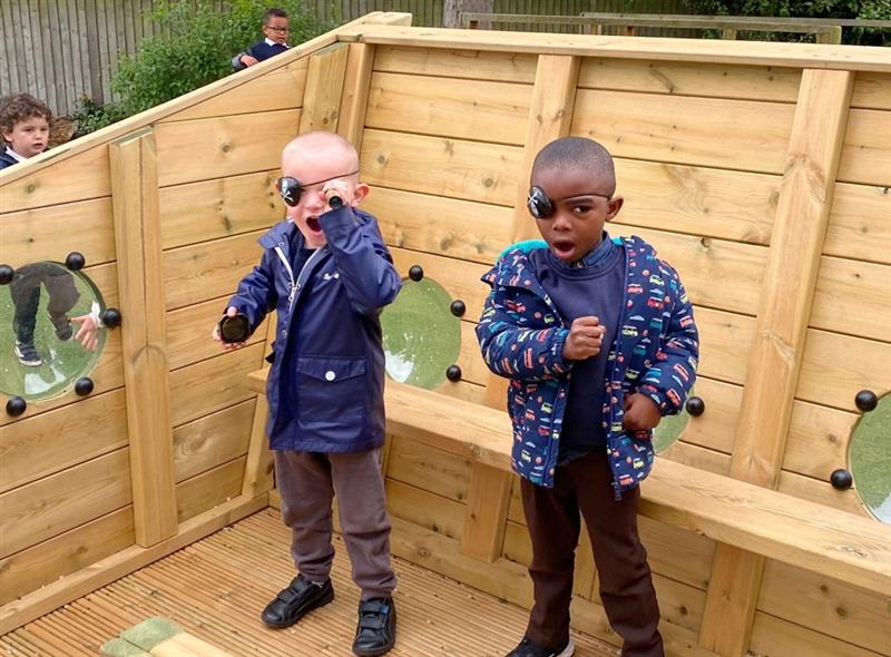 two little boys in navy waterproof coats wear eyepatches and look at the camera doing their best pirate impression
