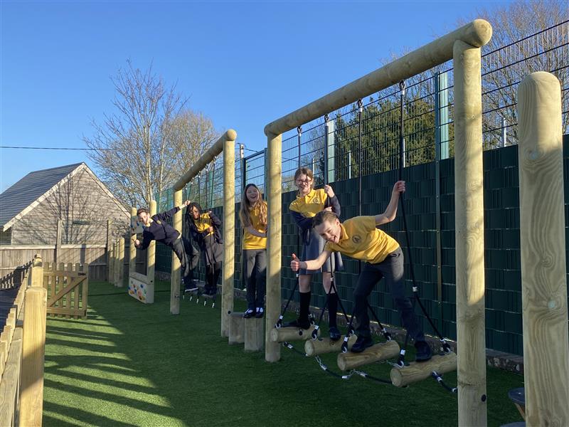 A class of children playing on the trim trail in their playground