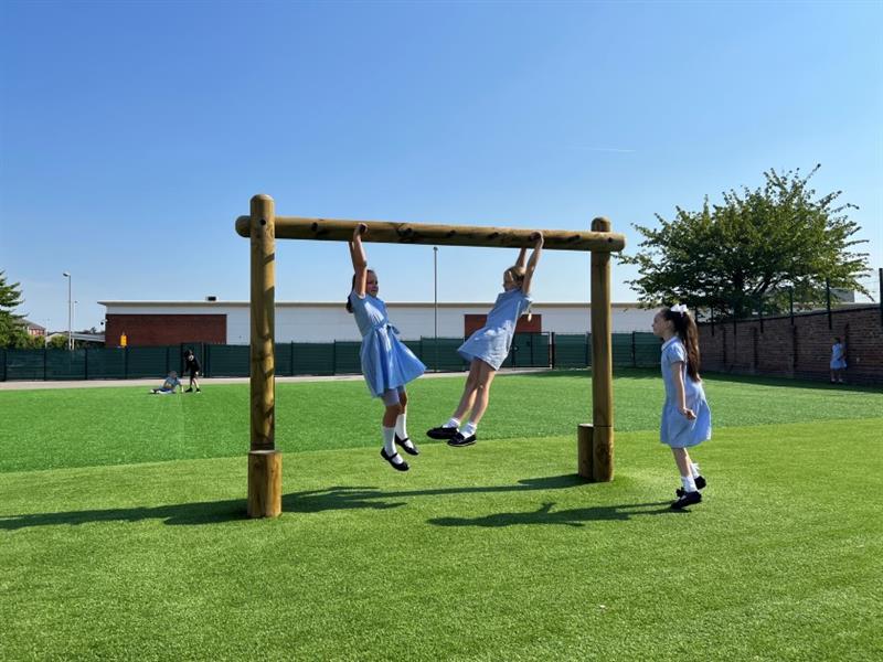 two children hang on the monkey bars in their active play playground