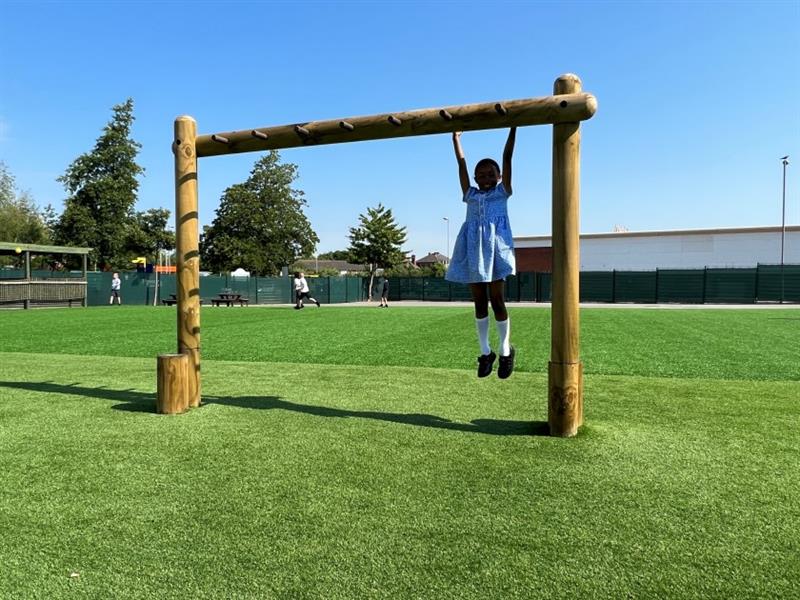 a little girl hangs from the monkey bars on the new trim trail