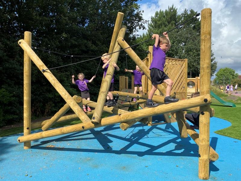 children in a purple uniform climb along on the bowfell climbing frame