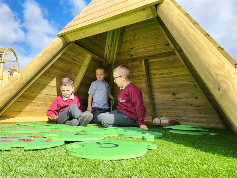 3 young boys playing in the wigwam den in their playground