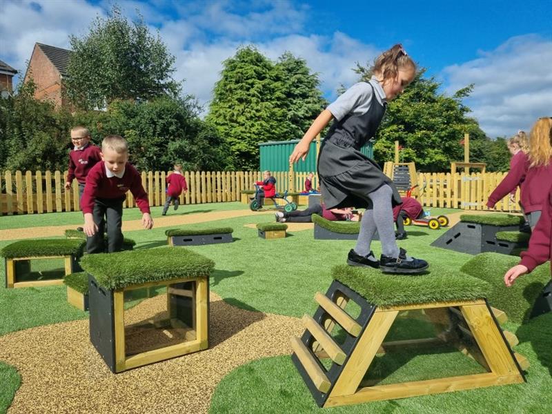 A small group of children jumping across the get set go blocks in their playground 