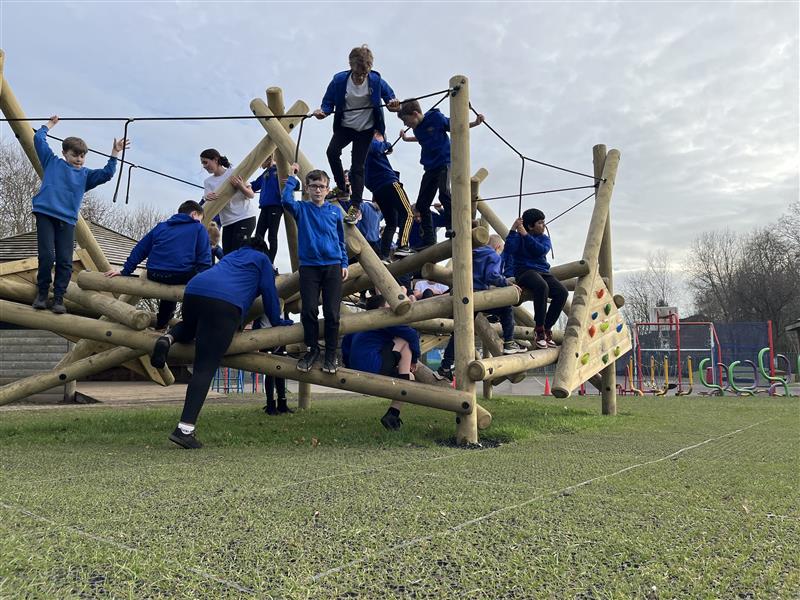 A class of children playing on the huge climbing frame in their school