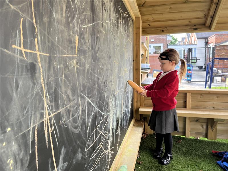 A young girl drawing on the chalk board in the playground