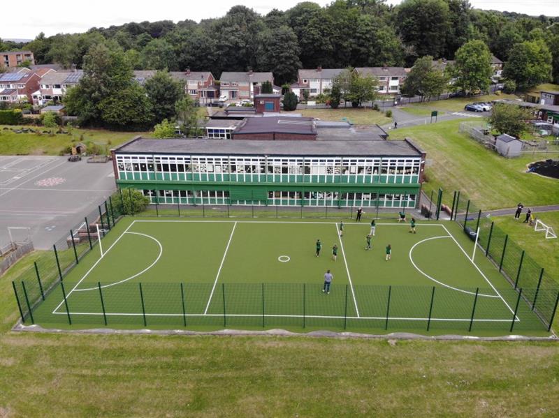 a birdseye view of the green artificial grass surfacing with children playing on the pitch