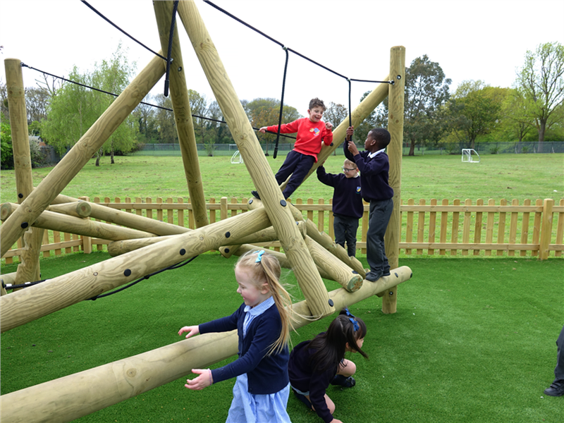 3 young children climbing on the climbing frame in their playground