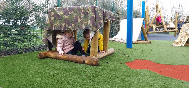 2 young children sat in the in and out shape in their playground development 