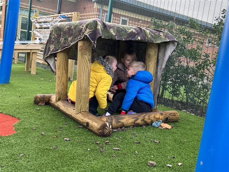 children sat in the timber shapes in their playground 