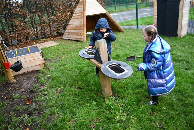 2 children playing in with the weighing scales in their new playground development