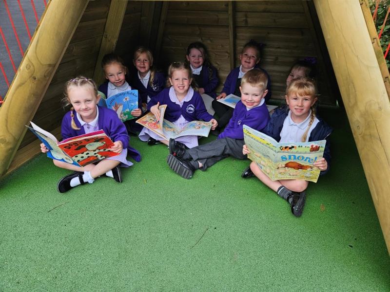 children sit and read books in the wigwam