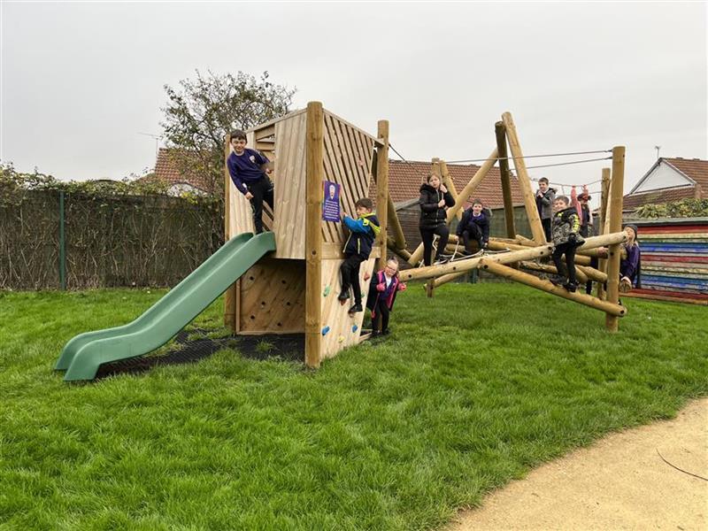 A class of children playing on the climbing frame in their playground setting