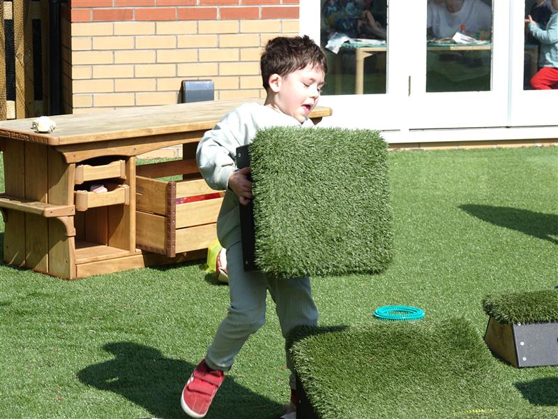 A young boy carrying one of the artificial blocks in his playground 