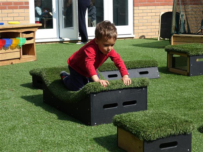 A young boy playing in on the moveable blocks in his playground 
