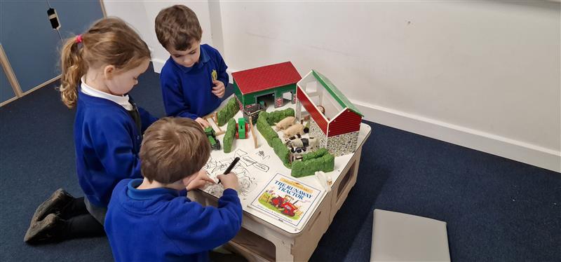 children sit and play on the low-level table with toys on top as they write on the wipe clean chalkboard and whiteboard tops