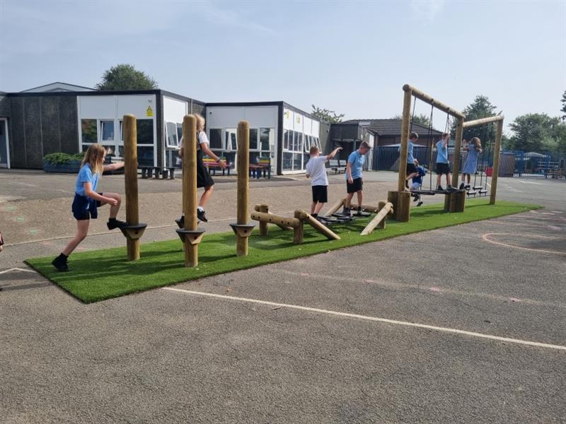 children played on the trim trail on the tarmacced playground with artificial grass under the trail