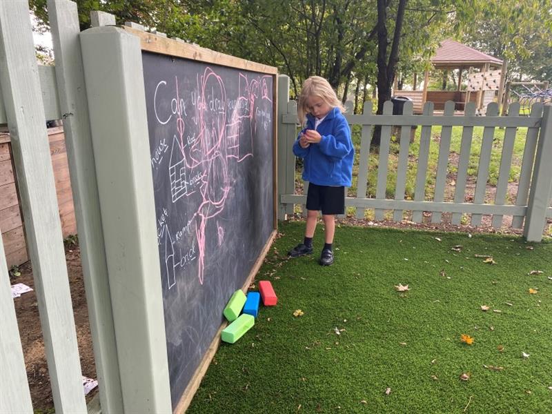 a little girl stands and writes on the chalkboard