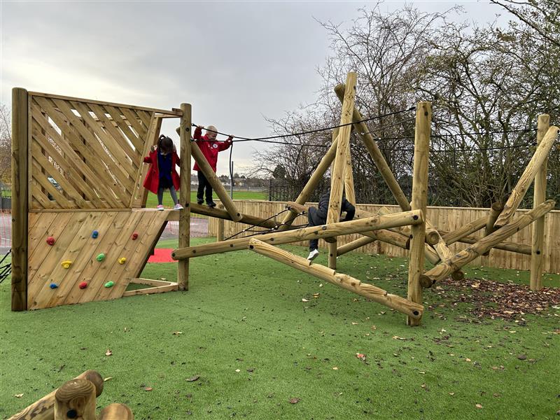 2 young children playing on the climbing frame at their primary school 