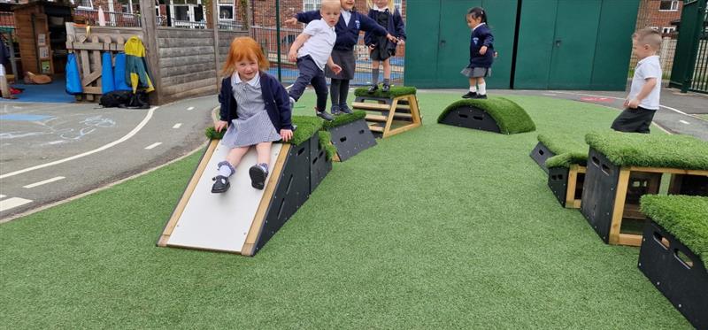 a little girl slides down the slide block in her new eyfs play area
