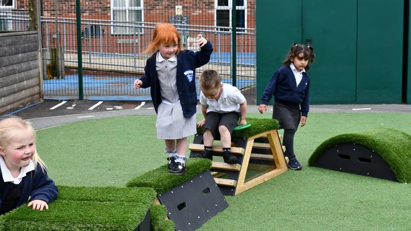 a little girl builds her climbing confidence on the climbing blocks in her new play area for the eyfs pupils