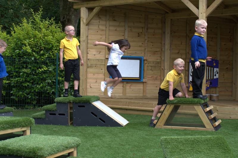 3 children climbing on the movable blocks in their playground 