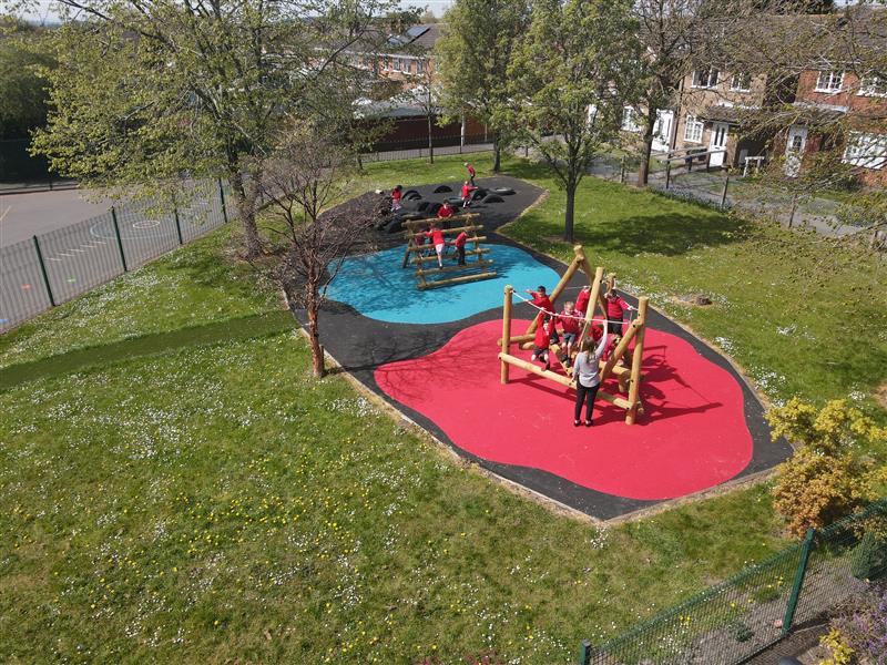 children playing on climbing frame which is on top of bright red wetpour, surrounded by black wetpour