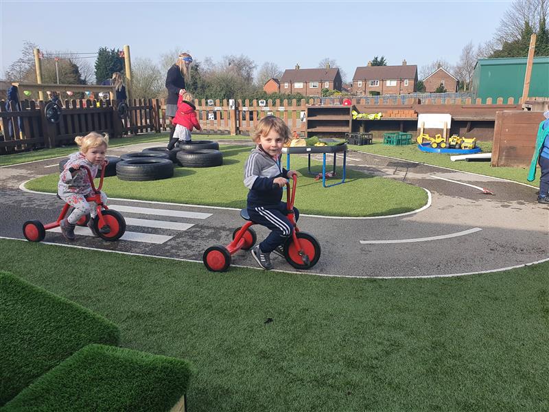 2 children racing trikes around a thermoplastic playground marking bike track