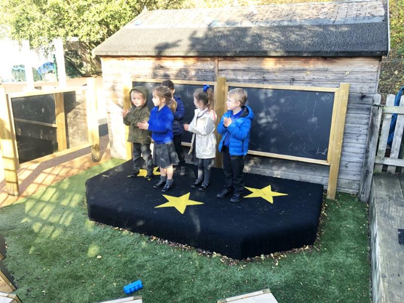 EYFS children performing a song on a playground stage