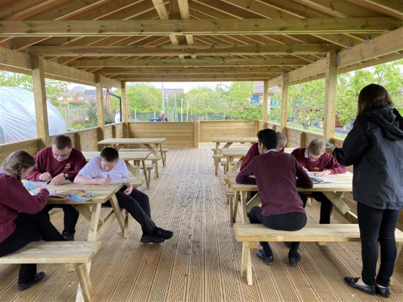 children sat on picnic benches under our canopy