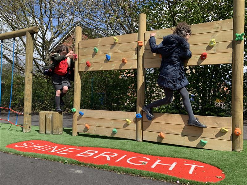 two children climbing on the climbing wall on our trim trail