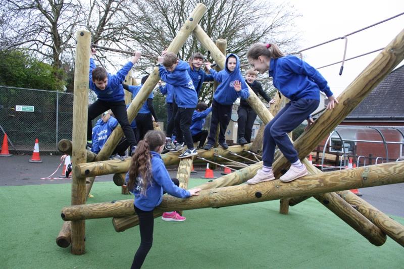 Children playing on Pentagon Play's Tryfan Climbing Frame installed onto artificial grass on their school playground