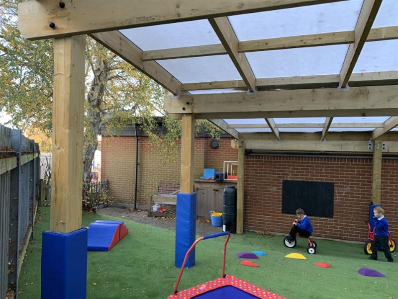 Children playing on artificial grass under a timber canopy