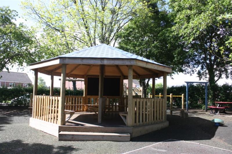 a outdoor gazbeo built by pentagon play with a decked base and step