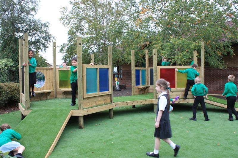 children climbing and walking through Pentagon Play's Twin Imagination Station installed over artificial grass.