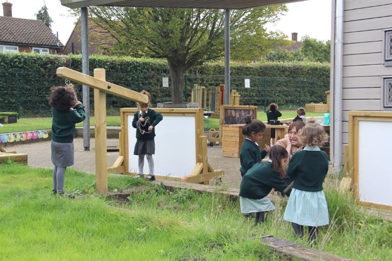 Nursery children playing with interactive playground fencing and Pentagon play weighing scales