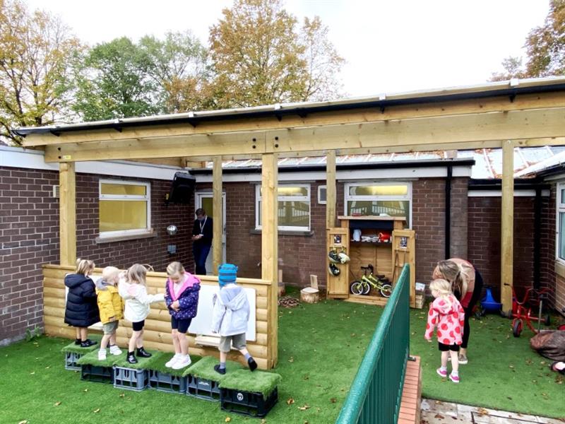 Children playing on artificial grass underneath a timber canopy