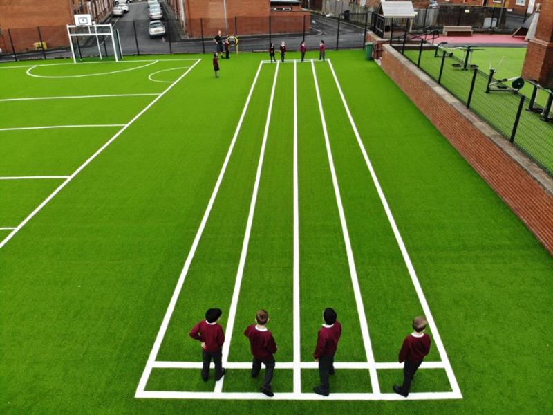 a sprint track with artificial grass surfacing and white lines indicating the track for the pupils to run on
