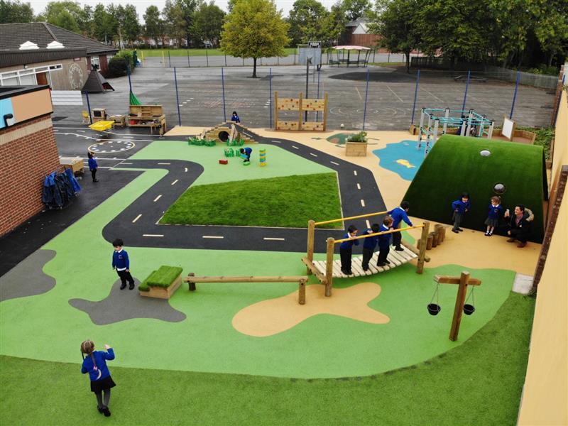 an entire play scheme with surfacing and timber play products such as a clatter bridge being played on by children in blue school uniform