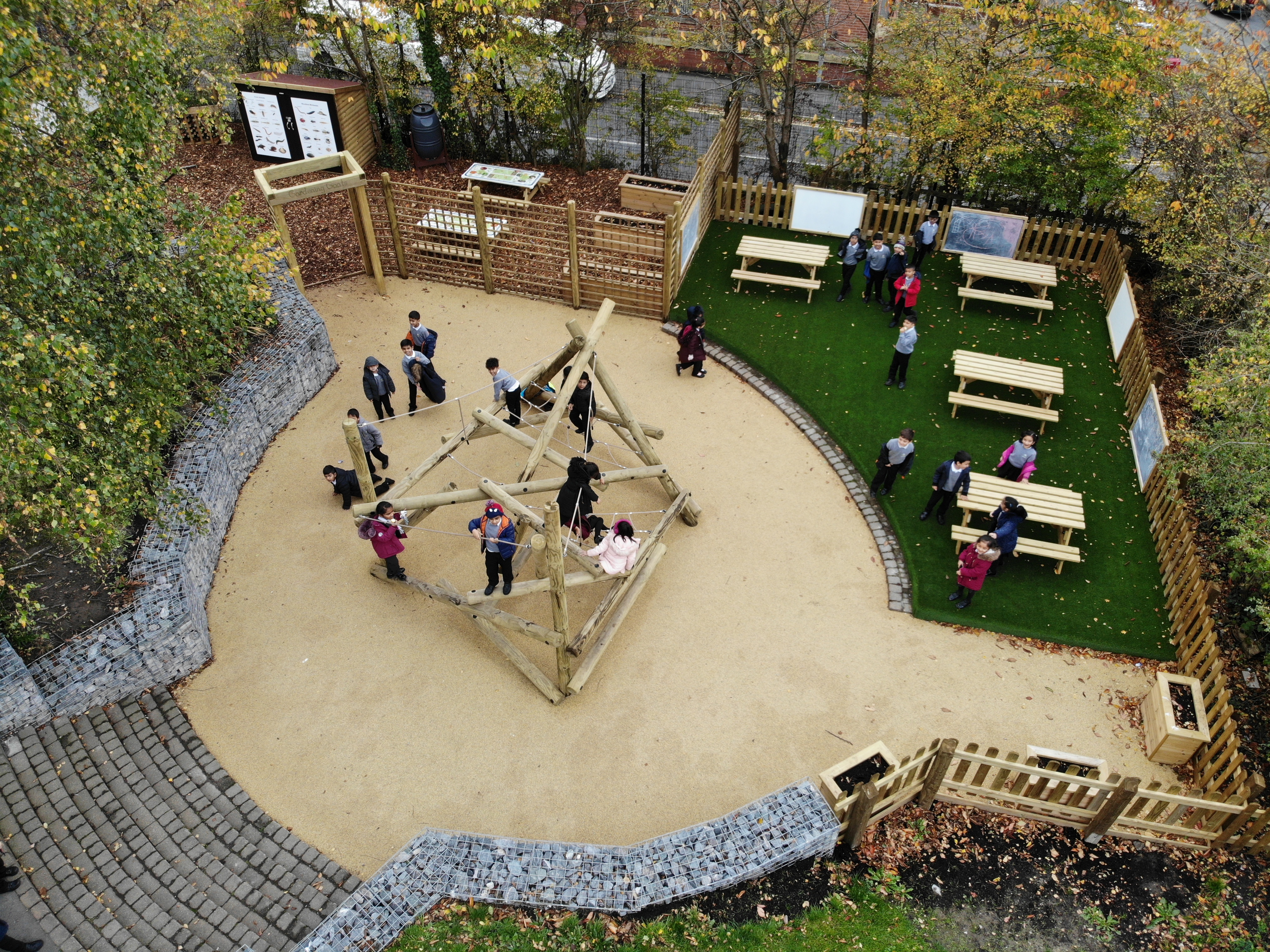 A climbing frame has been installed in the middle of a wetpour circle, with children climbing the structure.