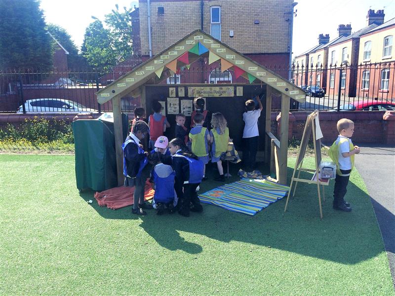 children clamber into the giant playhouse with chalkboard that is decorated with bunting and signs 