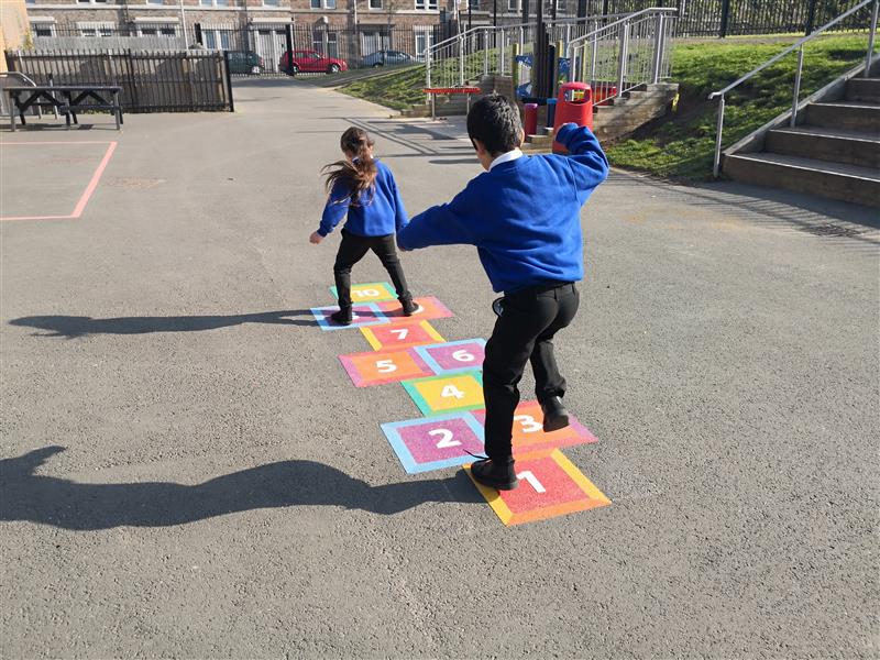 2 children playing on the hopscotch on there playgrounds