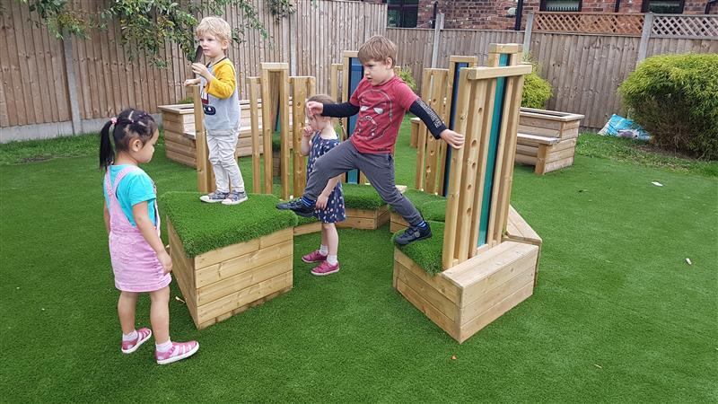 children stand on the grass topped seats and climb across them building their climbing confidence