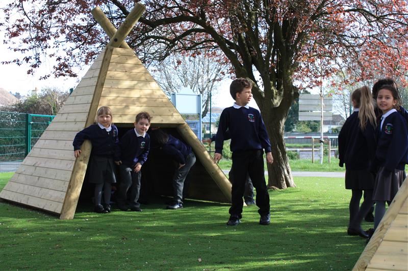 children playing inside of playground dens installed underneath the trees