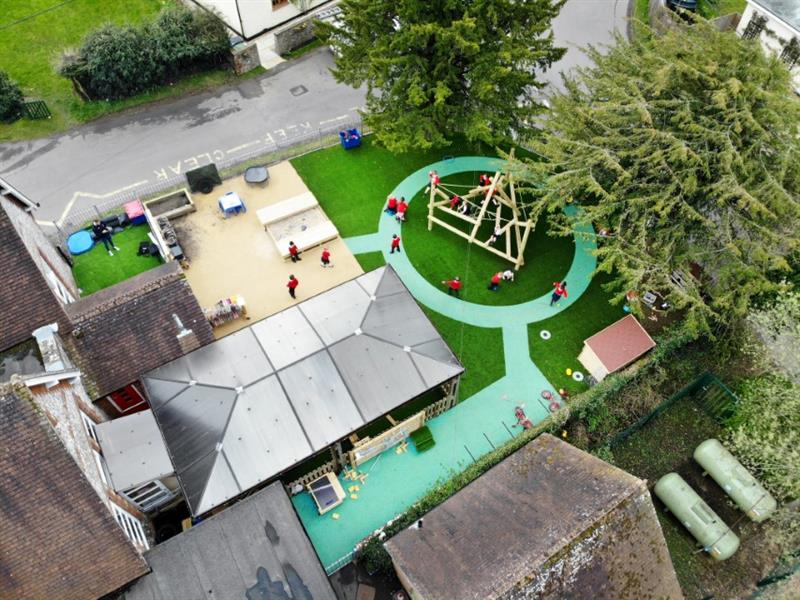 a birdseye view of the climbing frame with green artificial grass and beige wetpour