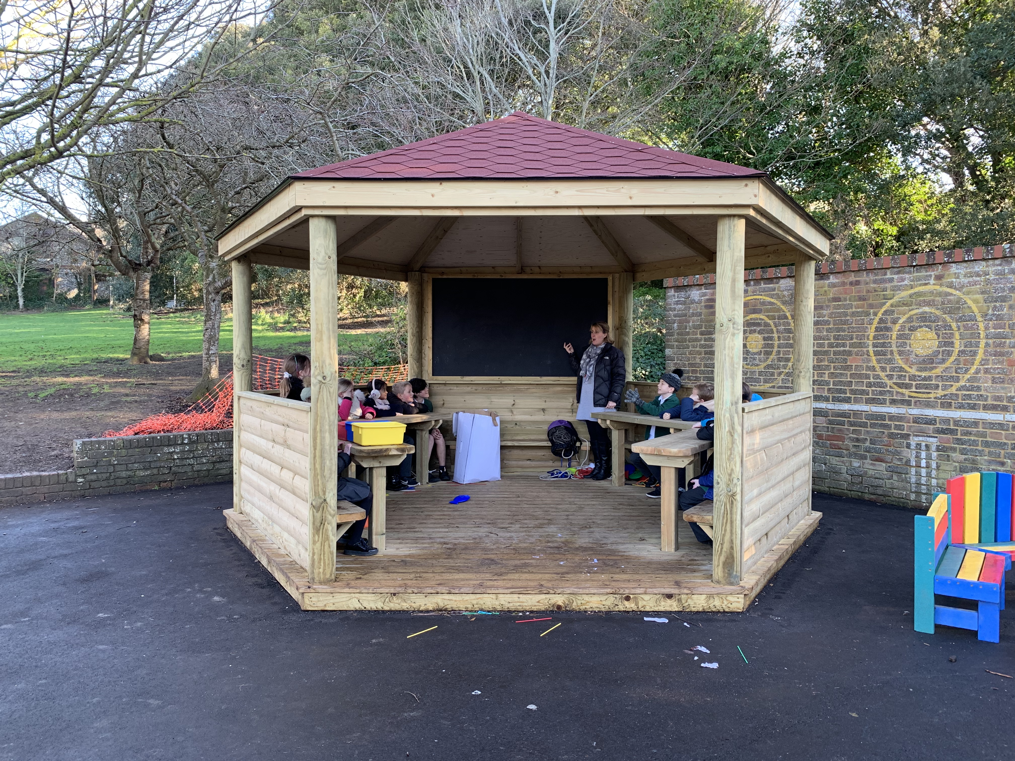 A teacher and her class are learning about phonics in an outdoor school canopy.